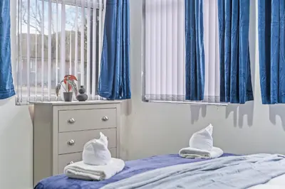 a bedroom with blue curtains and a bed with two pillows at Latimer Flat 2 - Spacious 2-Bed Apt - Sleeps 7 in Liverpool