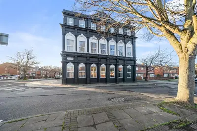 a black and white building on a street with a tree at Latimer Flat 2 - Spacious 2-Bed Apt - Sleeps 7 in Liverpool