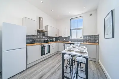 a kitchen with white cabinets and a island with stools at Latimer Flat 3 - Spacious 2-Bed Apt - Sleeps 6 in Liverpool