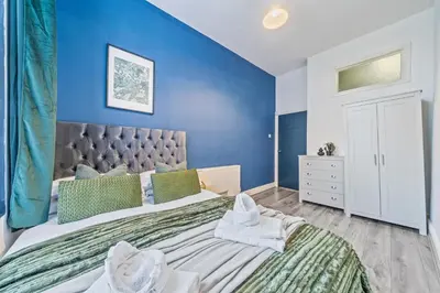 a bedroom with a large bed with a blue wall at Latimer Flat 3 - Spacious 2-Bed Apt - Sleeps 6 in Liverpool