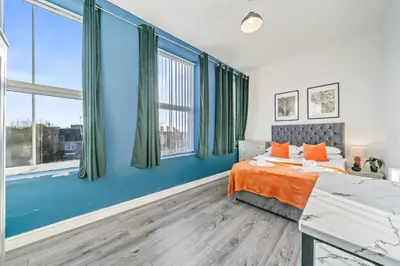 a bedroom with blue walls and a bed with orange pillows at Latimer Flat 4 - Spacious 2-Bed Apt - Sleeps 6 in Liverpool