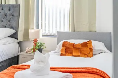 a bedroom with a bed with orange and white pillows at Latimer Flat 4 - Spacious 2-Bed Apt - Sleeps 6 in Liverpool