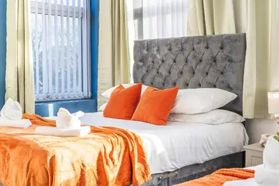 a bedroom with a bed with orange and white pillows at Latimer Flat 4 - Spacious 2-Bed Apt - Sleeps 6 in Liverpool
