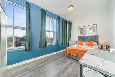 a bedroom with blue walls and a bed with orange pillows at Latimer Flat 4 - Spacious 2-Bed Apt - Sleeps 6 in Liverpool