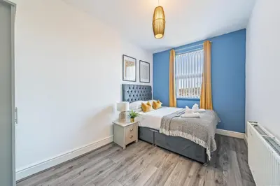 a bedroom with a bed with blue walls and a window at Latimer Flat 5 - Spacious 2-Bed Apt - Sleeps 7 in Liverpool