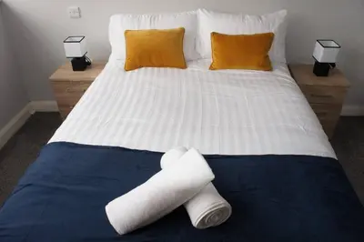 a bed with two rolls of towels on it at Melbourne House Apartment Near Train Station! in Accrington