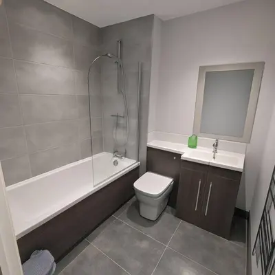 a bathroom with a toilet and a tub and a sink at Melbourne House Apartment Near Train Station! in Accrington