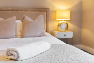 a white towel laying on a bed with a lamp at Stunning 3B Home, ideal for leisure & contractors in Clitheroe