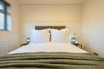a bedroom with a large bed with white sheets and pillows at Calgary Residence in Mellor