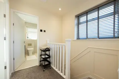 a white bathroom with a toilet and a staircase at Calgary Residence in Mellor