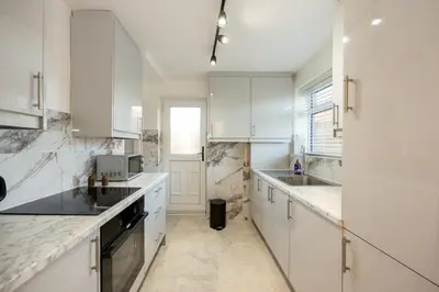 a kitchen with white cabinets and marble counter tops at Calgary Residence in Mellor