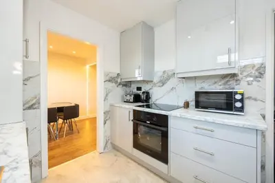 a kitchen with white cabinets and a microwave at Calgary Residence in Mellor