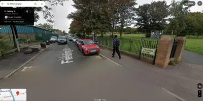 a man walking down a street next to a red car at COZY Apartment 4 in Liverpool
