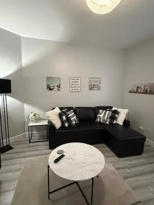 a living room with a black couch and a table at Adrian House Blackpool in Blackpool