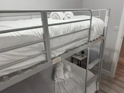 a bunk bed with white sheets and towels on it at Adrian House Blackpool in Blackpool