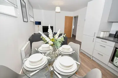 a dining room table with white plates and flowers on it at Modern 2 Bedroom Apartment in Central Wigan in Wigan