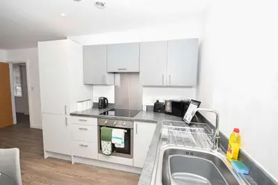 a kitchen with white cabinets and a sink at Modern 2 Bedroom Apartment in Central Wigan in Wigan