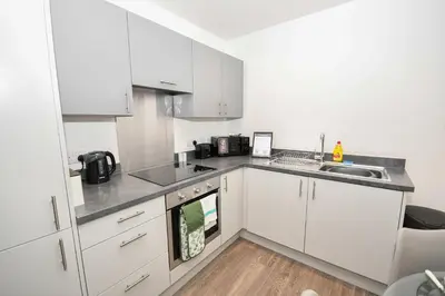 a kitchen with white cabinets and a sink at Modern 2 Bedroom Apartment in Central Wigan in Wigan