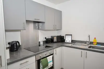 a kitchen with white cabinets and a sink at Modern 2 Bedroom Apartment in Central Wigan in Wigan