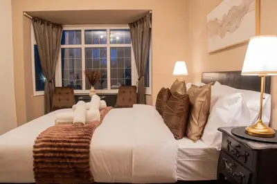 a bedroom with a white bed with a window at Elegant Bolton Home Garden Free Parking Sleeps 7 in Bolton