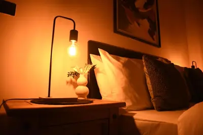 a lamp on a table next to a bed at Elegant Bolton Home Garden Free Parking Sleeps 7 in Bolton
