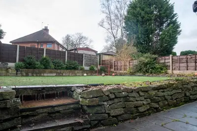 a garden with a retaining wall and a fence at Elegant Bolton Home Garden Free Parking Sleeps 7 in Bolton