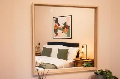 a reflection of a bedroom with a bed in a mirror at Elegant Bolton Home Garden Free Parking Sleeps 7 in Bolton