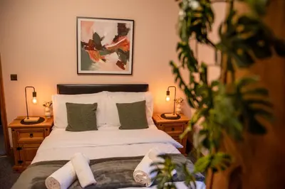 a bedroom with a bed with two lamps and a plant at Elegant Bolton Home Garden Free Parking Sleeps 7 in Bolton