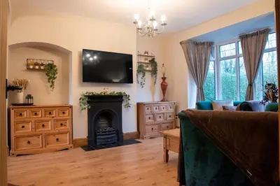 a living room with a fireplace and a tv on the wall at Elegant Bolton Home Garden Free Parking Sleeps 7 in Bolton