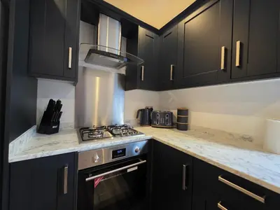 a kitchen with black cabinets and a stove top oven at Anfield 4 min walk Sleeps 7 4BR 5Bed 3Bathrooms in Liverpool