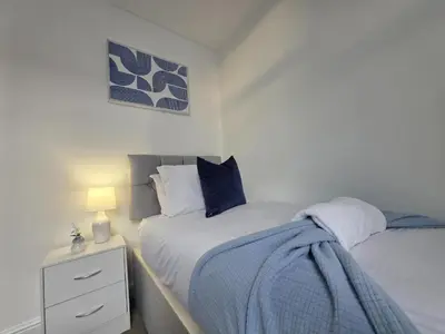 a bedroom with two beds and a night stand with a lamp at Anfield 4 min walk Sleeps 7 4BR 5Bed 3Bathrooms in Liverpool