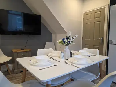 a white table with white dishes and flowers on it at Anfield 4 min walk Sleeps 7 4BR 5Bed 3Bathrooms in Liverpool