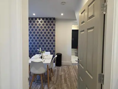 a room with a table and chairs and a blue wall at Anfield 4 min walk Sleeps 7 4BR 5Bed 3Bathrooms in Liverpool