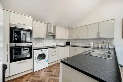 a kitchen with white cabinets and a washer and dryer at Colquitt House - Air Host & Stay - 8BR Sleeps 16 in Liverpool