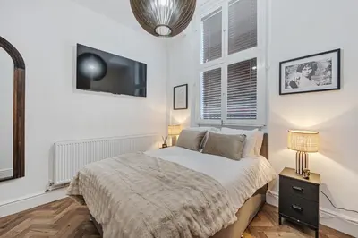 a bedroom with a bed and a tv on the wall at Colquitt House - Air Host & Stay - 8BR Sleeps 16 in Liverpool