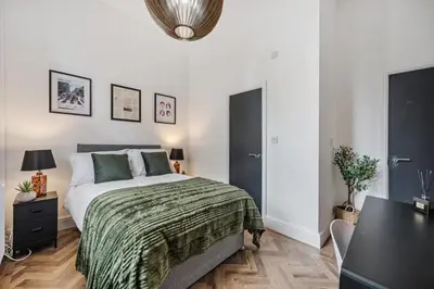 a bedroom with a bed with a green blanket at Colquitt House - Air Host & Stay - 8BR Sleeps 16 in Liverpool