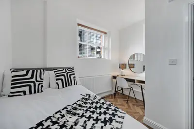 a white bedroom with a bed and a desk at Colquitt House - Air Host & Stay - 8BR Sleeps 16 in Liverpool