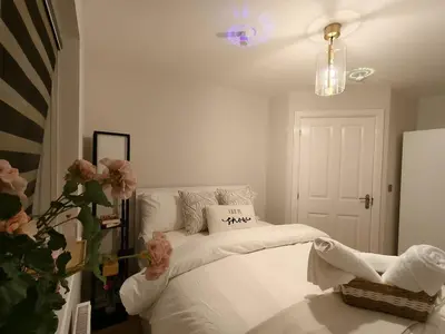 a bedroom with a bed with white sheets and pink flowers at Hanani House in Liverpool