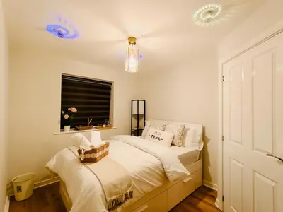 a bedroom with a bed with white sheets and a window at Hanani House in Liverpool