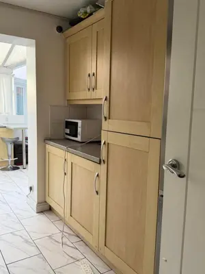 a kitchen with wooden cabinets and a microwave at Nightingale Roomz in Lower Darwen