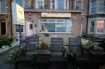 a row of benches in front of a building with flowers at Shipping Lanes Hotel in Morecambe
