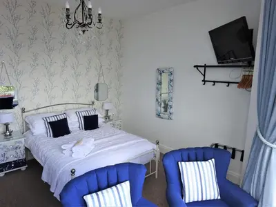 a bedroom with a bed and two blue chairs at Shipping Lanes Hotel in Morecambe