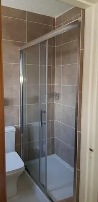 a shower with a glass door next to a toilet at Shipping Lanes Hotel in Morecambe