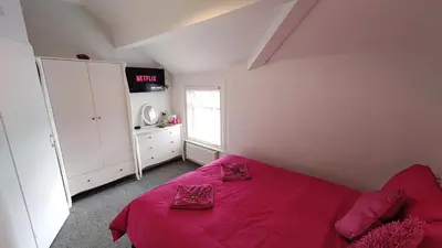 a bedroom with a bed with pink sheets and a window at The Castleton in Blackpool