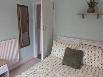 a bedroom with a bed with a pillow and a mirror at STANLEY HOUSE MORECAMBE Modern spacious 3 bed family home near seafront in Heysham