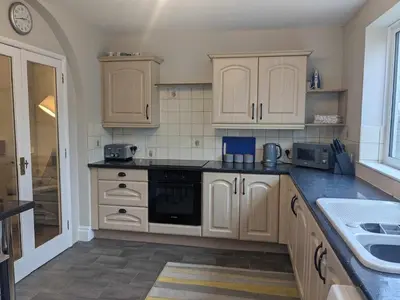 a kitchen with white cabinets and a sink in it at STANLEY HOUSE MORECAMBE Modern spacious 3 bed family home near seafront in Heysham