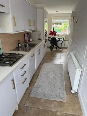 a kitchen with white cabinets and a sink and a table at Luxurious Ribble Valley Home in Clitheroe