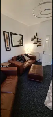 a living room with brown leather couches and a mirror at The Victorian Terrace in Morecambe
