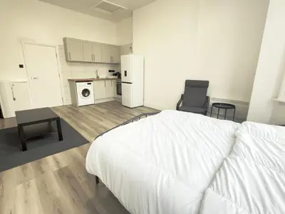 a bedroom with a white bed and a kitchen at Princes road hidden gem in Liverpool