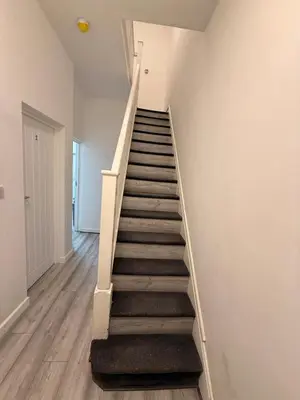 a staircase in a room with white walls and wooden floors at Stylish Dream Home with 4 En-Suite Bedrooms in Liverpool